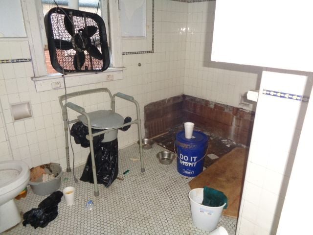 bathroom featuring tile patterned flooring, toilet, and tile walls