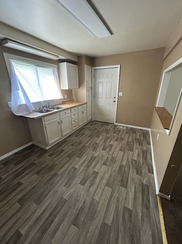 kitchen with dark hardwood / wood-style flooring, white cabinetry, and sink