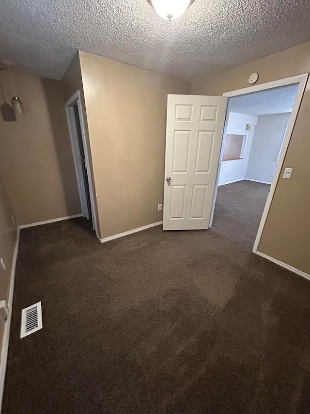 carpeted empty room with a textured ceiling