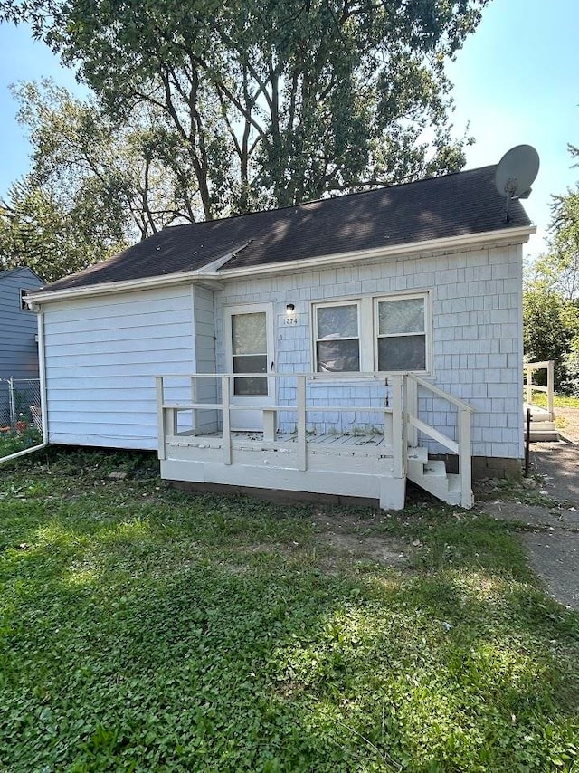 rear view of property featuring a deck and a yard