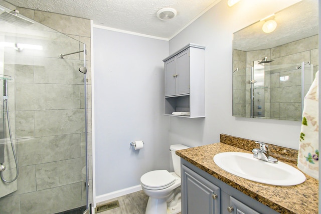 bathroom with vanity, hardwood / wood-style flooring, toilet, a textured ceiling, and a tile shower