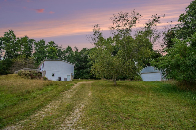 yard at dusk with an outbuilding and a garage