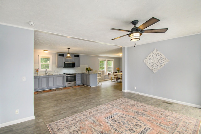 unfurnished living room with ceiling fan, dark hardwood / wood-style flooring, and sink