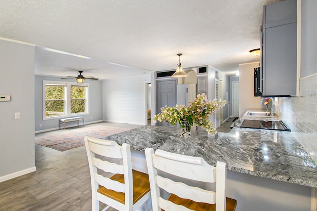 kitchen with tasteful backsplash, gray cabinets, kitchen peninsula, and hanging light fixtures