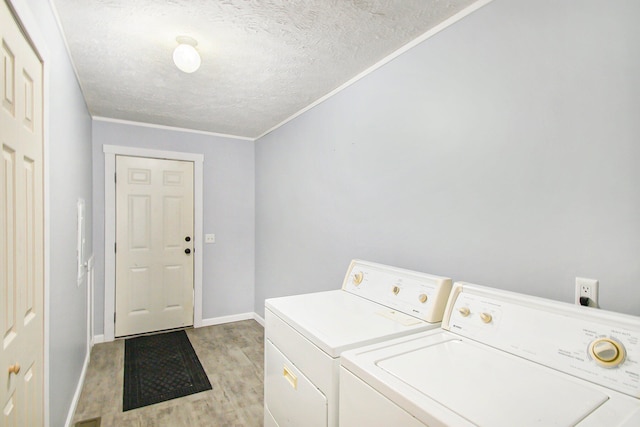 washroom featuring washing machine and clothes dryer, crown molding, light hardwood / wood-style flooring, and a textured ceiling