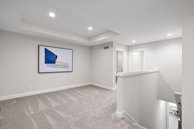 carpeted empty room with a raised ceiling