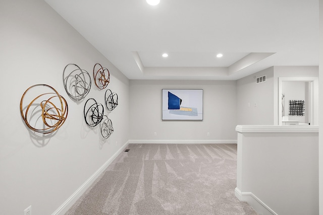carpeted spare room with a raised ceiling