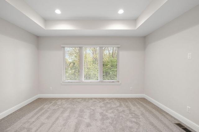 empty room with a tray ceiling and light colored carpet