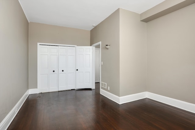 unfurnished bedroom featuring dark hardwood / wood-style floors and a closet