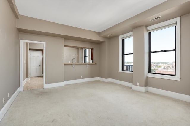 spare room featuring sink and light colored carpet