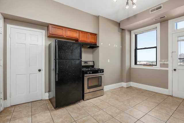 kitchen featuring gas stove, black refrigerator, light tile patterned floors, and plenty of natural light