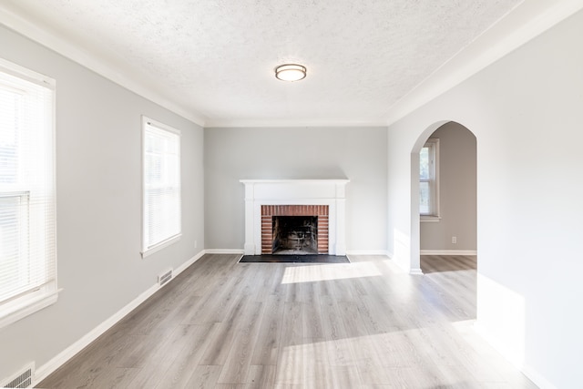 unfurnished living room featuring a brick fireplace, a textured ceiling, and light hardwood / wood-style flooring