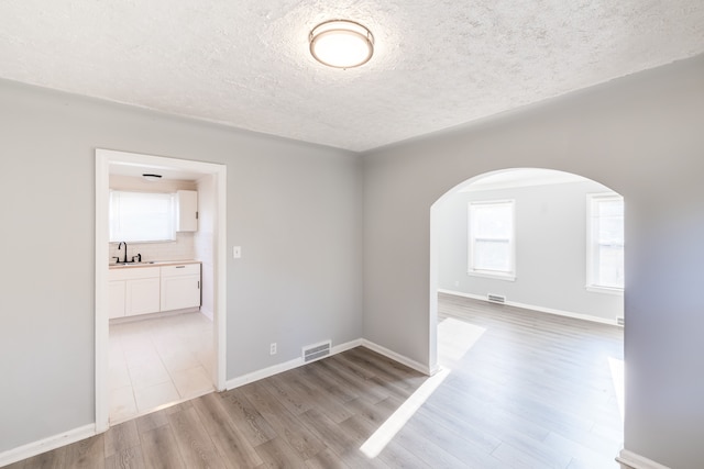 spare room featuring a textured ceiling, light hardwood / wood-style flooring, and sink