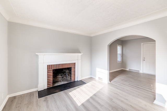 unfurnished living room with a fireplace, light hardwood / wood-style floors, and a textured ceiling