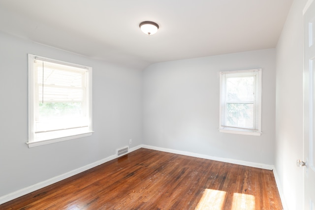 unfurnished room featuring dark hardwood / wood-style floors and vaulted ceiling