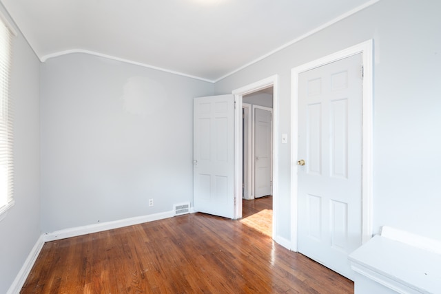 unfurnished bedroom with crown molding and dark wood-type flooring