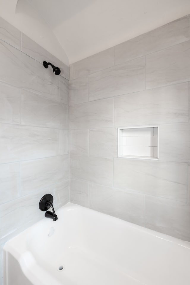 bathroom with lofted ceiling and tiled shower / bath