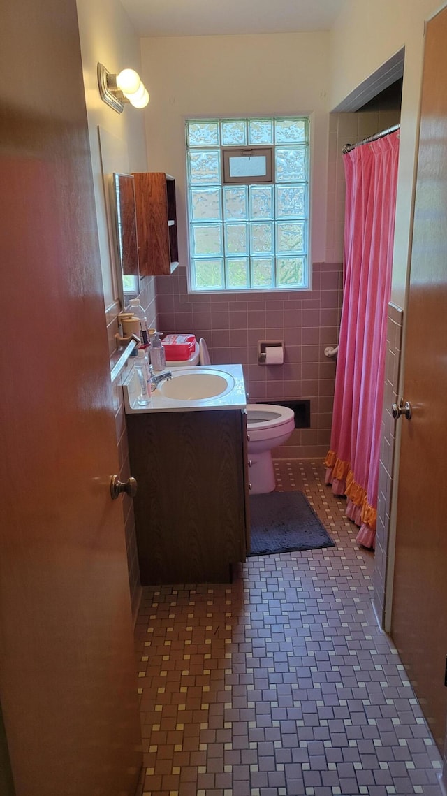 bathroom featuring vanity, tile patterned flooring, toilet, tile walls, and walk in shower