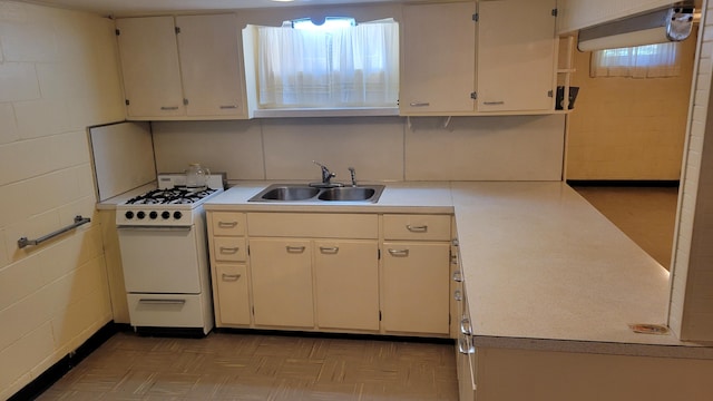 kitchen with white cabinetry, white gas range, and sink