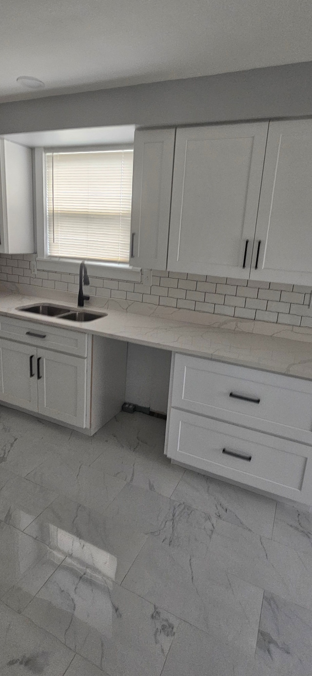 kitchen with decorative backsplash, light stone counters, white cabinetry, and sink