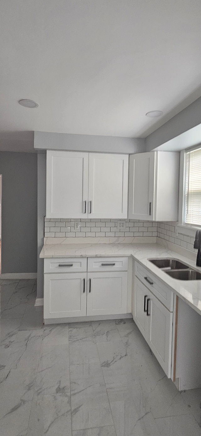 kitchen with white cabinets, backsplash, and sink