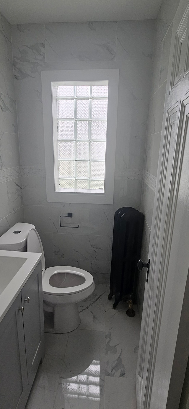 bathroom with vanity, tile walls, and toilet