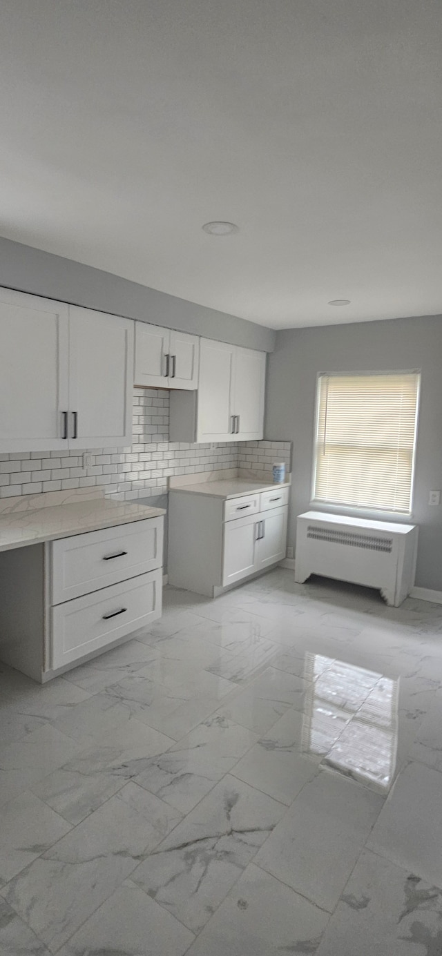 kitchen with backsplash, white cabinetry, and radiator heating unit