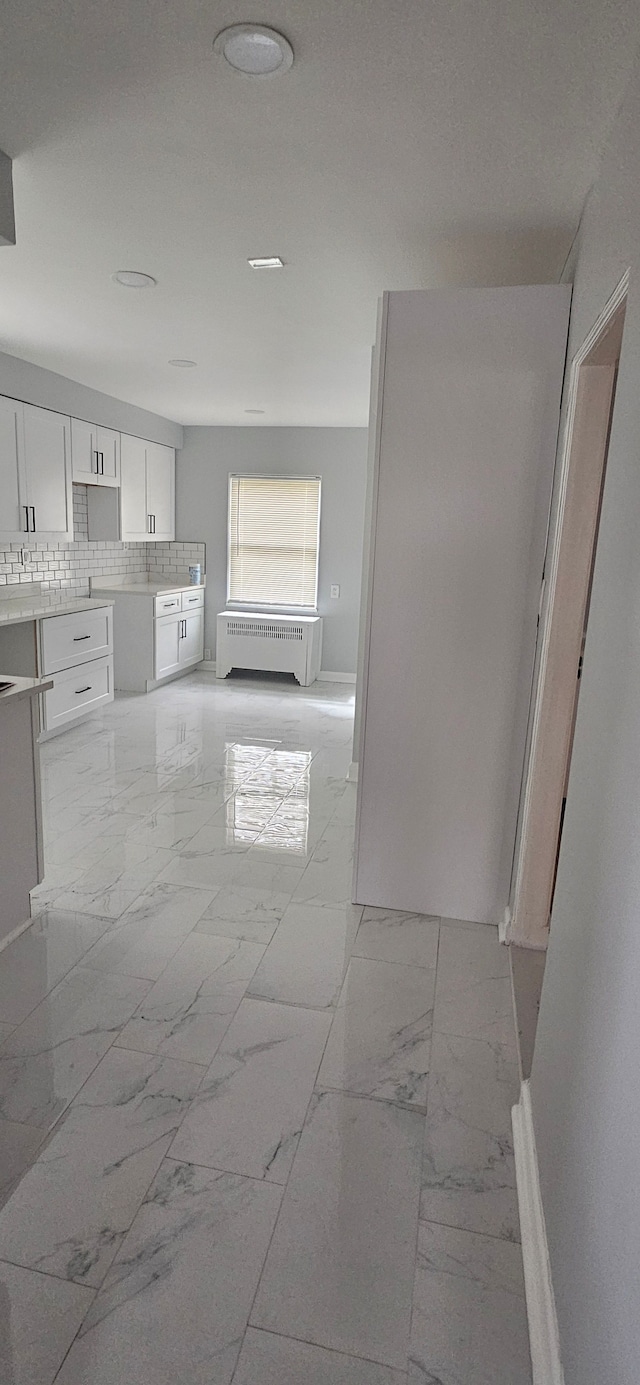 kitchen with radiator heating unit, backsplash, and white cabinetry