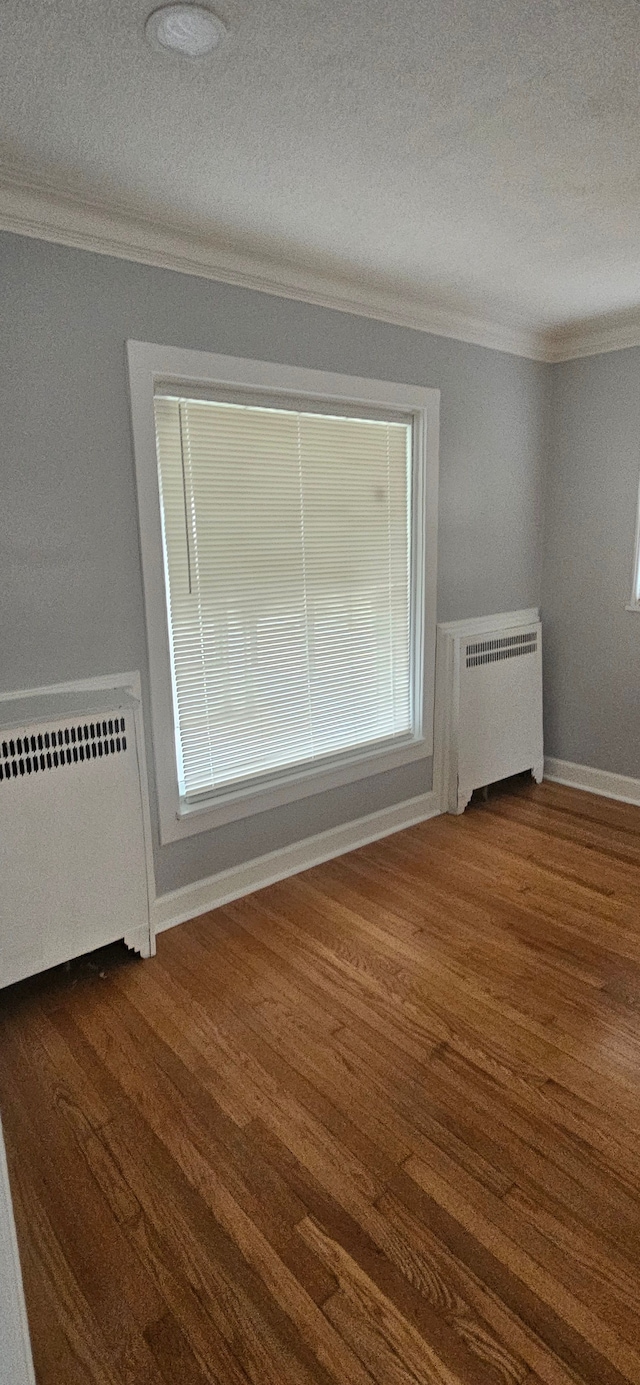 unfurnished room with a textured ceiling, radiator, and dark wood-type flooring