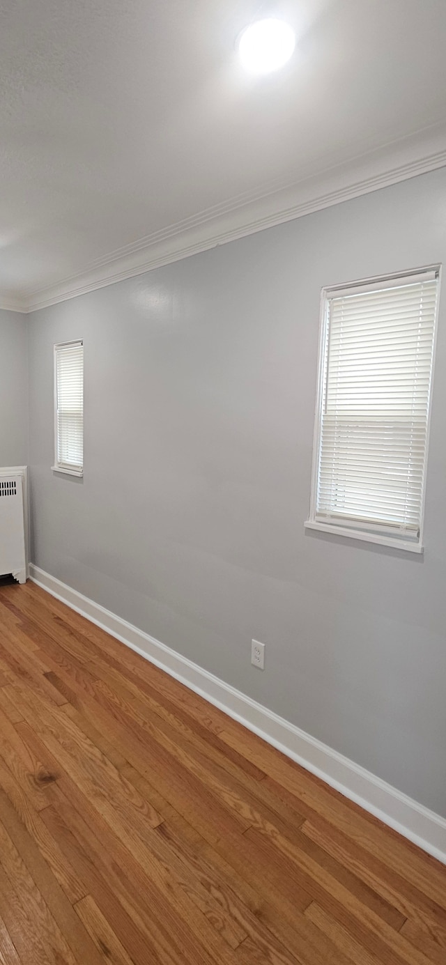 unfurnished room featuring hardwood / wood-style floors, ornamental molding, and radiator