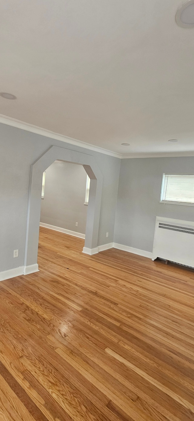 interior space featuring radiator heating unit, ornamental molding, and light hardwood / wood-style flooring