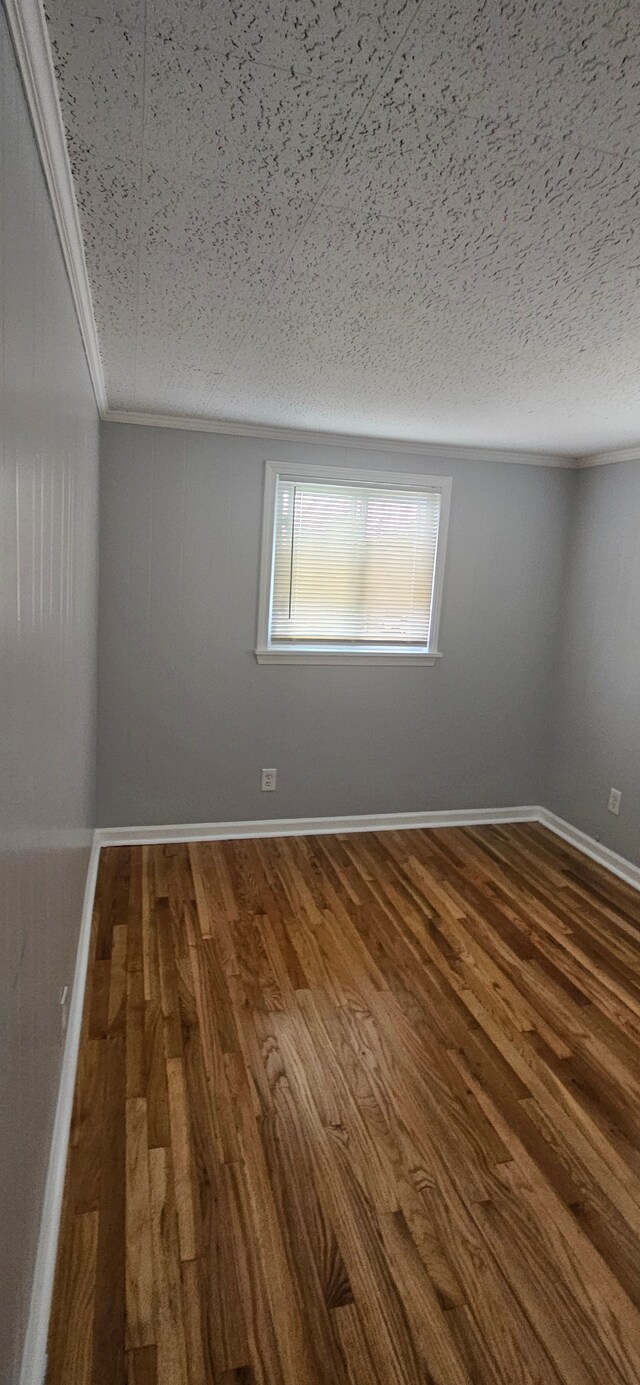 unfurnished room featuring a textured ceiling, hardwood / wood-style flooring, and crown molding