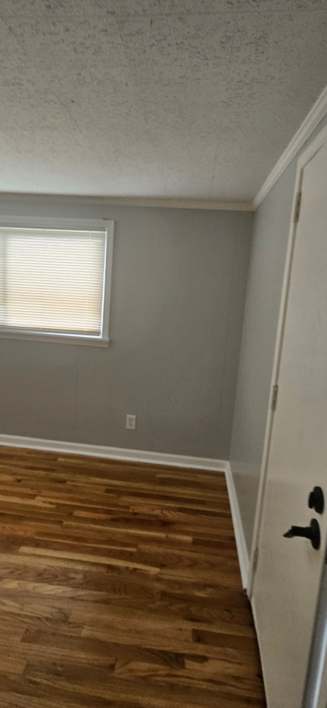 empty room featuring dark hardwood / wood-style floors, ornamental molding, and a textured ceiling