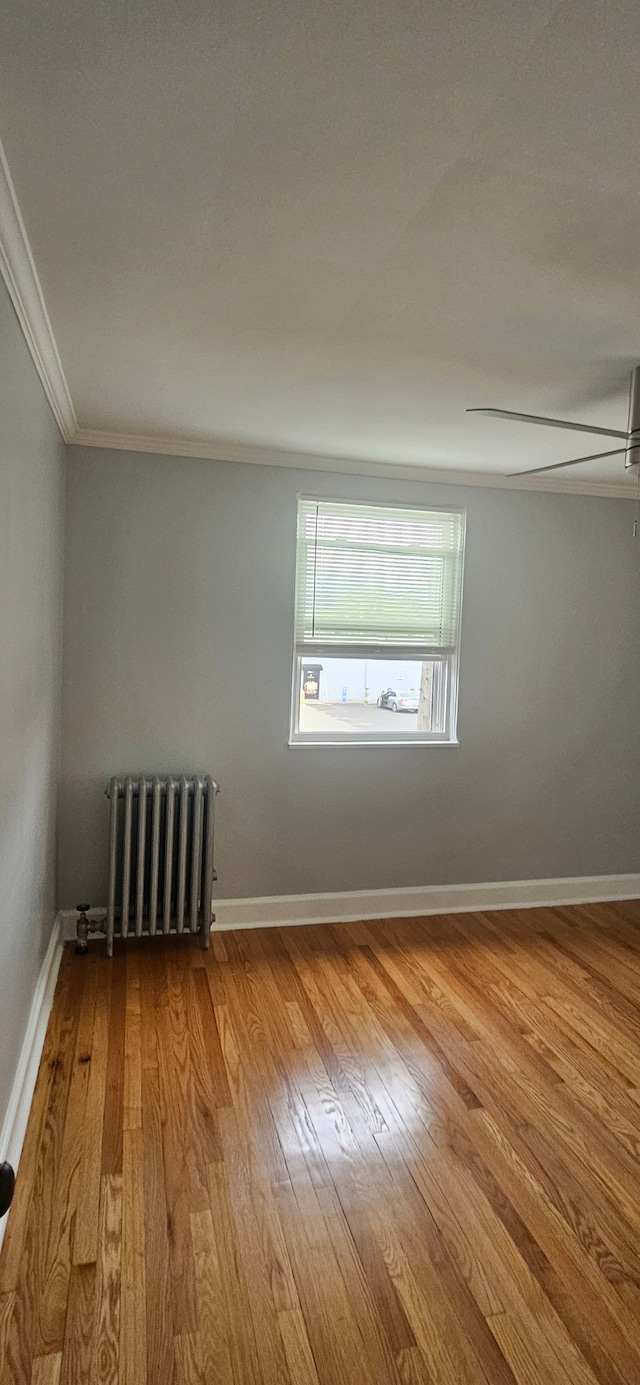 spare room with radiator, ceiling fan, ornamental molding, and light wood-type flooring