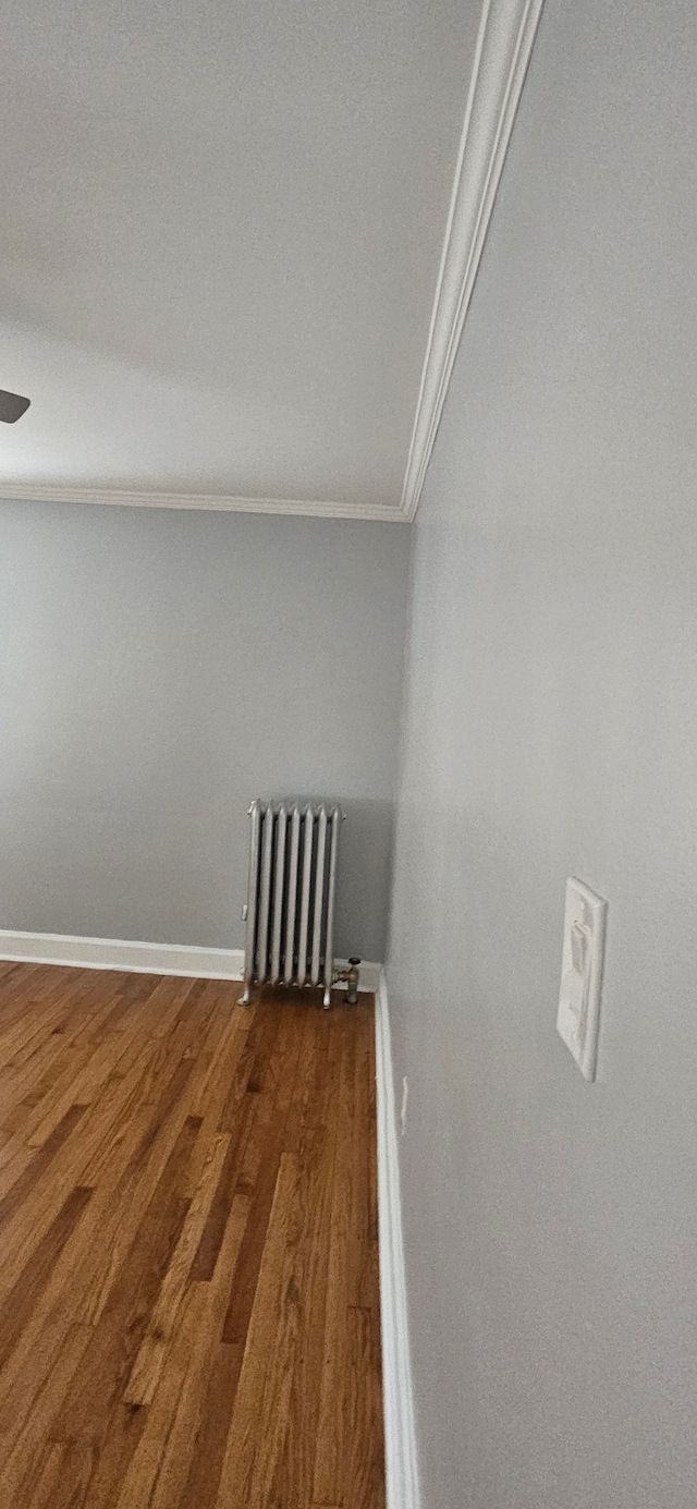 washroom with dark hardwood / wood-style floors, radiator heating unit, and crown molding