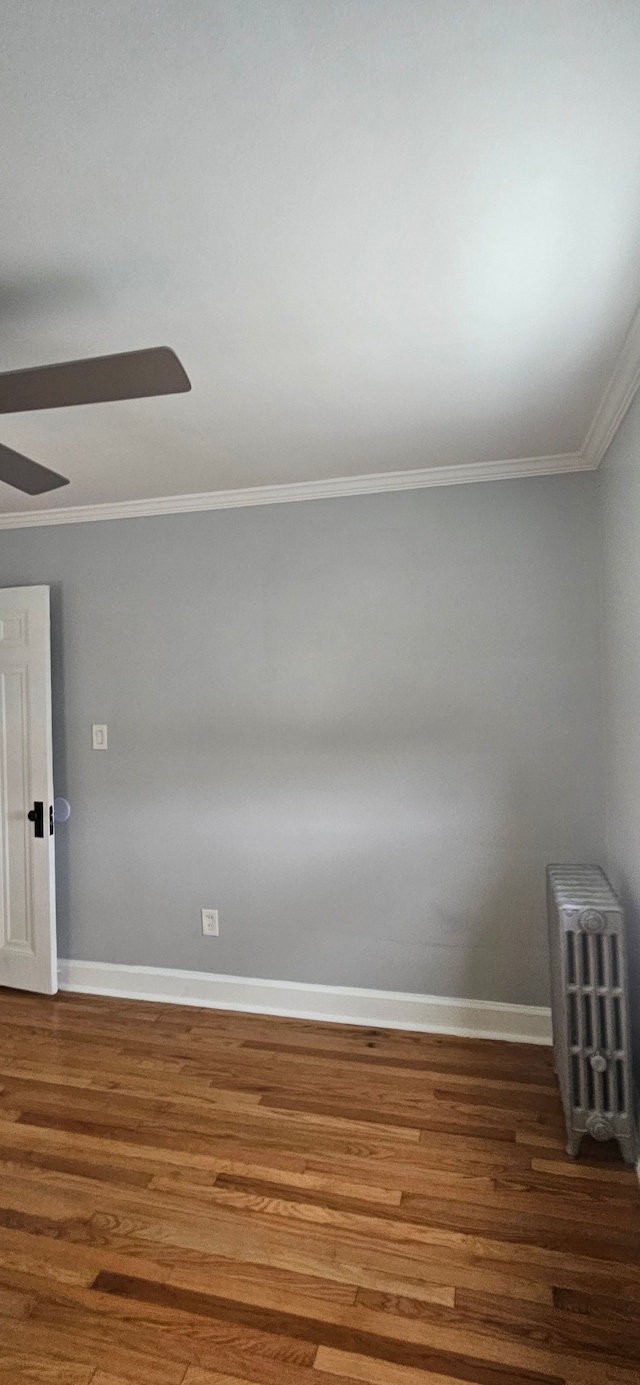 unfurnished room featuring dark hardwood / wood-style floors, radiator heating unit, and crown molding