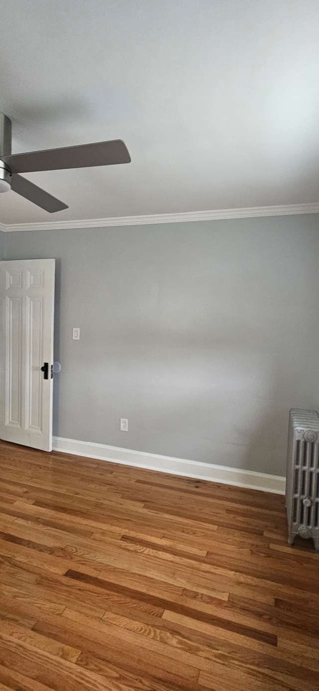 empty room featuring hardwood / wood-style floors, radiator heating unit, ceiling fan, and ornamental molding