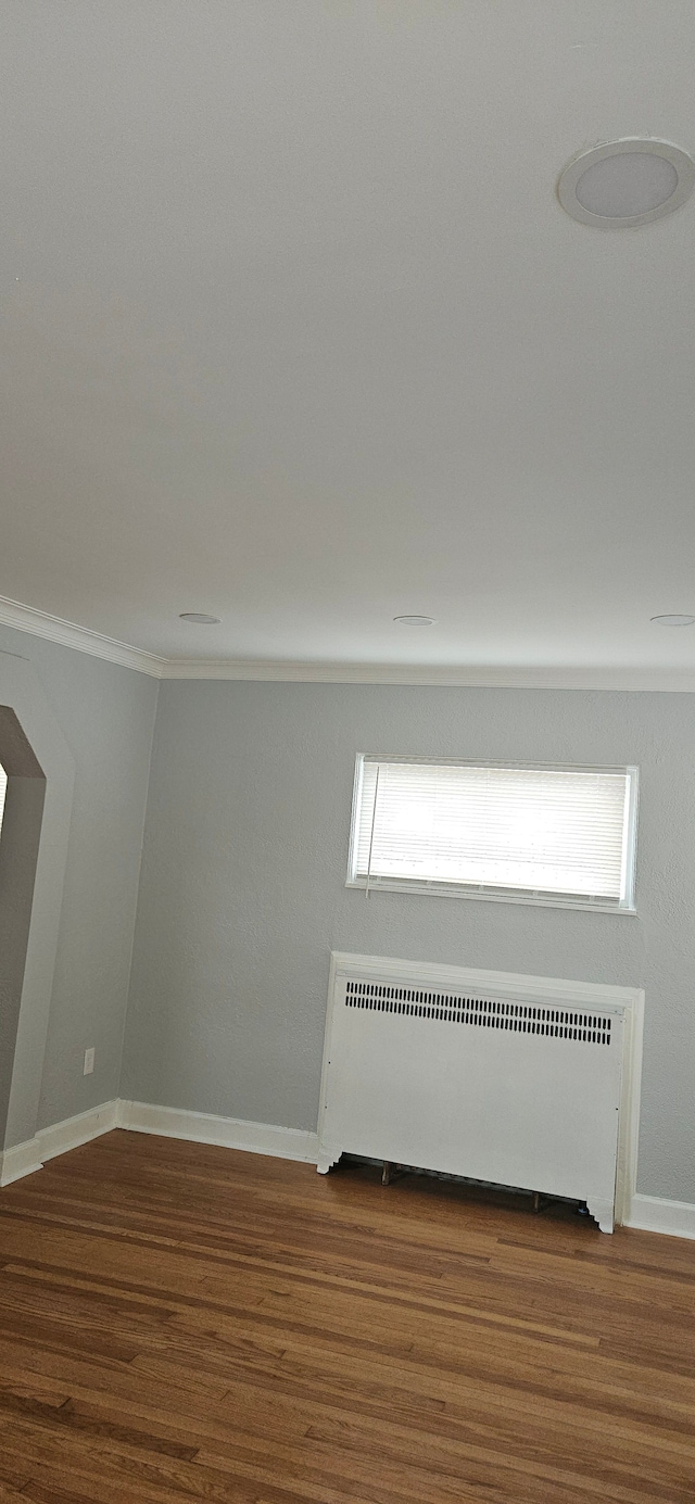 empty room with hardwood / wood-style floors and radiator heating unit