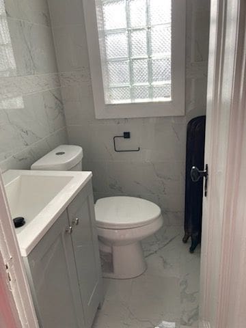 bathroom with vanity, tile walls, and toilet