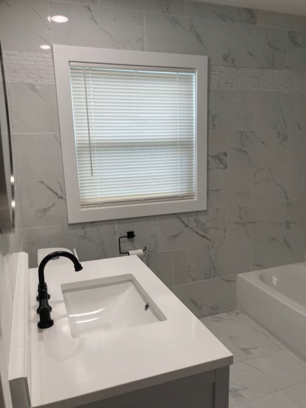 bathroom with a bathtub, vanity, and tile walls