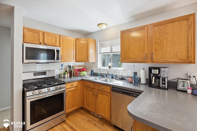 kitchen with light wood-type flooring, stainless steel appliances, and sink