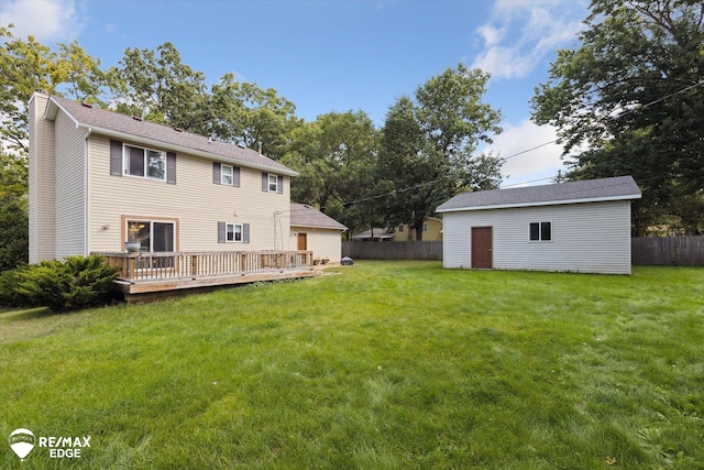 back of property with a lawn, an outbuilding, and a deck