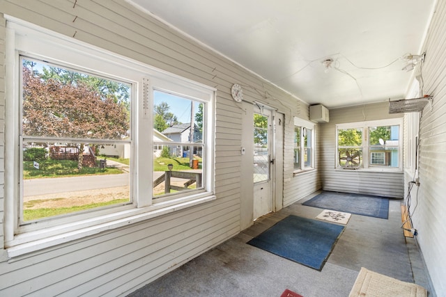 unfurnished sunroom featuring a healthy amount of sunlight and an AC wall unit