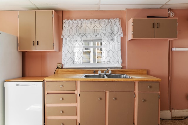 kitchen featuring a drop ceiling, white appliances, sink, and cream cabinets