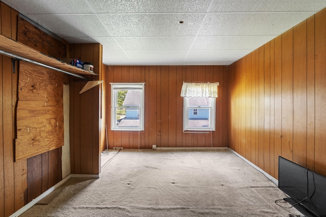 interior space with a paneled ceiling and wood walls