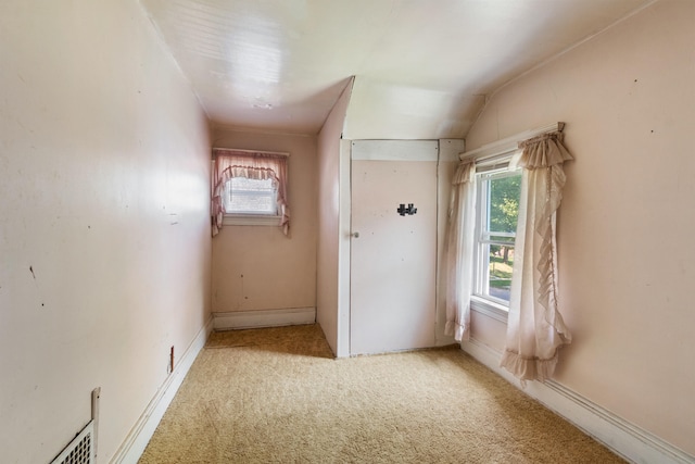 spare room featuring light carpet and vaulted ceiling