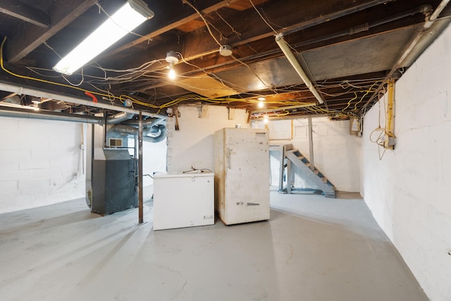 basement with white refrigerator and heating unit