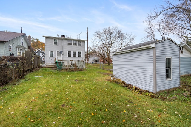 back of property with a deck, an outdoor structure, and a lawn