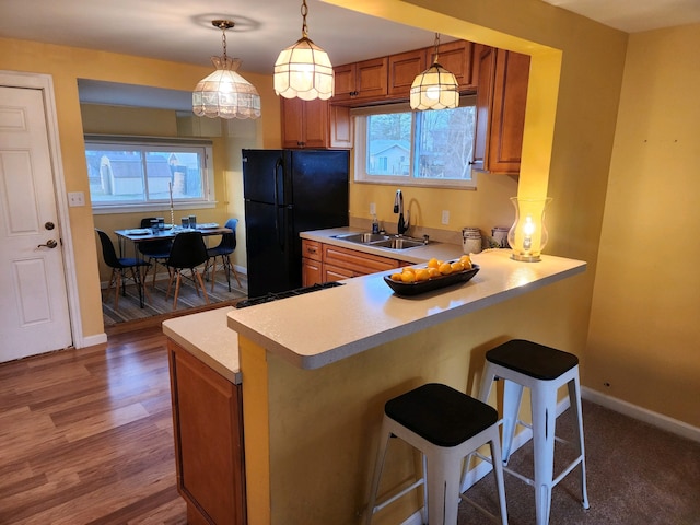 kitchen with sink, a breakfast bar area, black refrigerator, kitchen peninsula, and pendant lighting