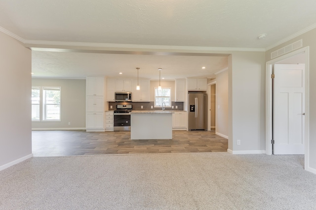 kitchen with white cabinetry, a center island, hanging light fixtures, appliances with stainless steel finishes, and light wood-type flooring